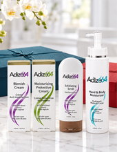Load image into Gallery viewer, Adize64 skincare gift set displayed in front of teal and red gift boxes on a marble counter.