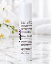 Load image into Gallery viewer, Adize64 Organic Lip Balm in a white 5 ml tube on a marble counter with white orchids in the background