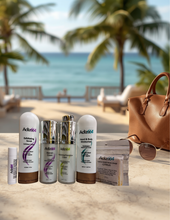 Load image into Gallery viewer, Adize64 Travel Kit with six skincare products on a seaside table beside sunglasses and a tan travel bag.
